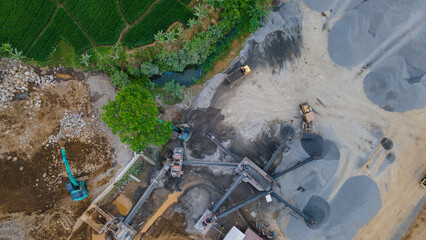 Mining Work in Quarry Industrial Site, Excavator and Wheel Dozer near Rock Crusher Facility from Above © katakaneh