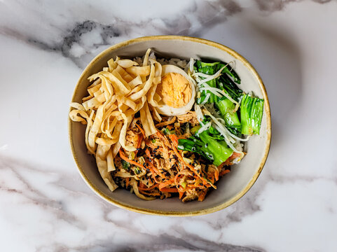 "Nasi Orak Arik" or scrambled rice is a typical Indonesian breakfast consisting of shredded chicken cooked spicy, boiled vegetables, pieces of boiled egg, and crackers as a complement.