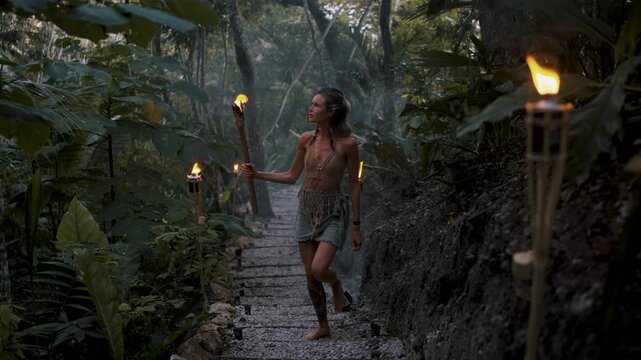 Woman holding torch while exploring mystical jungle trail in Peten