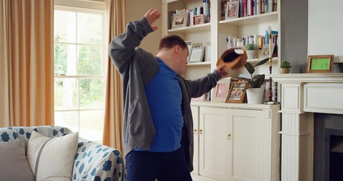 Man, dancing and fun in lounge, education and celebration for finished project on laptop or success. Student, rhythm and person with down syndrome on study break, achievement and hat movement in home