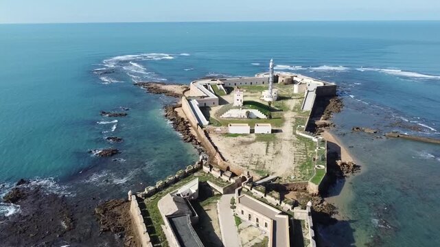 C&aacute;diz. Spain. Aerial view of Santa Catalina Castle. La Caleta Beach. View of a 17th-century military fortification next to a sea of ​​vibrant colors and waves crashing against the rocks.