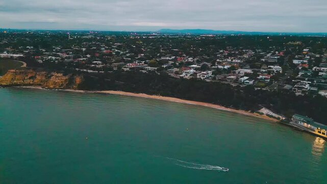 Cinematic 4K drone footage panning horizontally to capture Half Moon Bay beach, calm sea waters, and the historic HMVS Cerberus shipwreck beneath clear evening skies.