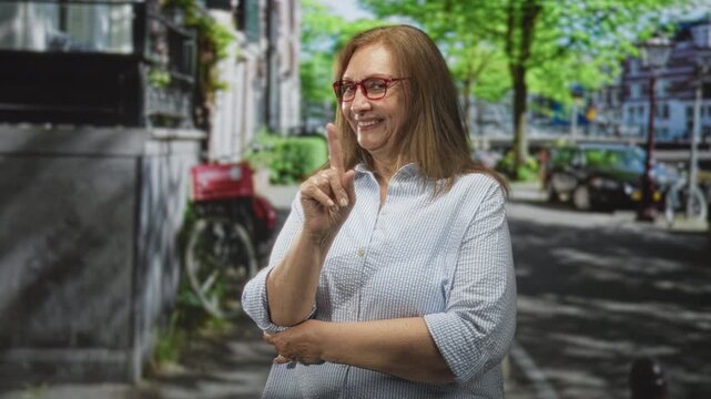 Woman points finger on street beside bicycle and parked cars, wearing glasses and casual shirt; friendly reminder.