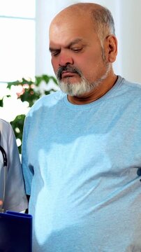 Indian Asian male doctor walks with a senior patient in a hospital passage, explaining the case report and procedure. He provides expert guidance, ensuring clarity, confidence, and quality healthcare