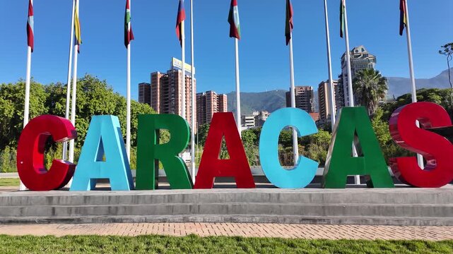 Caracas Bella sign, Public space located on Gran Cacique Guaicaipuro highway, directly across from entrance to Caracas Botanical Garden, with flagpoles displaying various flags a