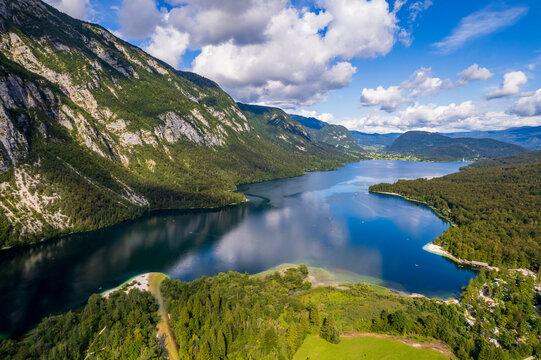 Lake Bohinj surrounded by green mountains, Slovenia. Scenic drone view of majestic alpine lake Bohinj in Triglav national park Slovenia with blue water and green forest slopes on a sunny summer day