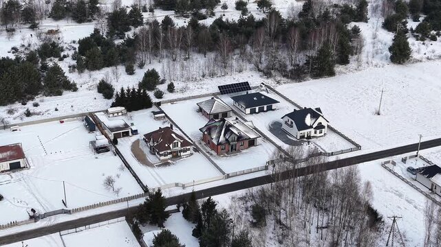 Aerial winter neighborhood showing roof snow melting differences