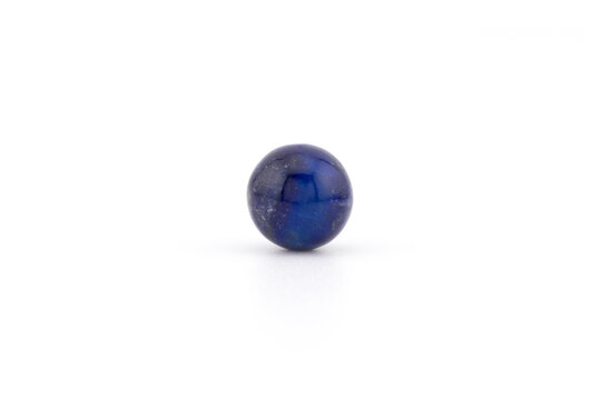 A small lapis lazuli sphere rests on a white background. The surface is smooth and shiny. Light reflects off the stone, showing its natural color