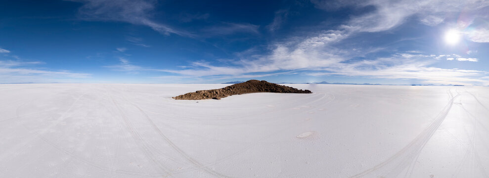 Vast white salt flat with island under a sunny sky