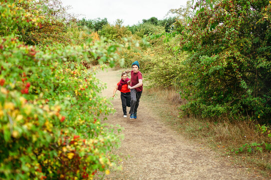 Siblings running along countryside trail during outdoor adventure