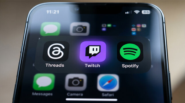 Threads, Twitch, and Spotify mobile logo icons on a screen smartphone iPhone. Threads is a social media app, Twitch is a live streaming platform, and Spotify is a music and podcast streaming service.