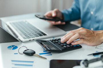 A male accountant calculating annual car tax, income and expense calculations, and analyzing...