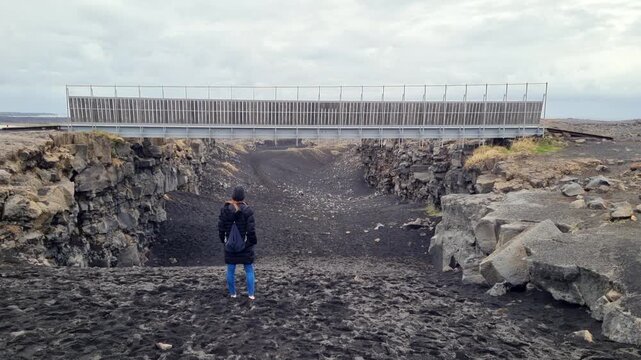 Female traveler admiring the Bridge Between Continents, a rift valley marking the Mid Atlantic Ridge on the Reykjanes peninsula