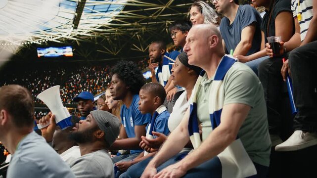 Multigenerational soccer fans watching tense moment from crowded stadium stands, decisive moment of intensity and anxiety with crowd energy.