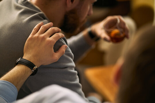 Young adult men supporting friend while drinking alcohol, showing male friendship, empathy, social bonding. Useful for mental health, addiction support, counseling campaigns, close up