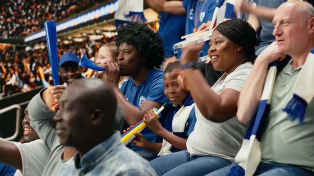 Young soccer fan cheering with blue supporters during live football match in packed stadium filled with cheering supporters, family outing captures fatherhood and role model during soccer experience.