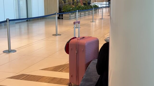 Pink suitcase with red neck pillow waiting at Chisinau Airport departure area before flight Moldova, Chisinau 