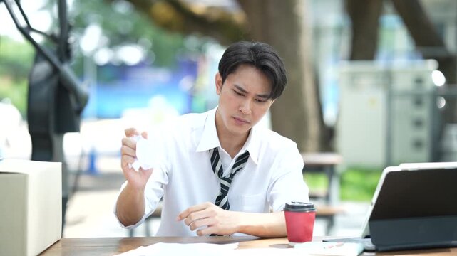 Young professional reviewing documents at an outdoor workspace, showing concern about employment, financial matters, career decisions, and business challenges.