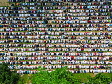 Joypurhat, Bangladesh - 28 May 2026: Aerial view of a large crowd of Muslim men performing mass prayer in neat rows on colorful mats outdoors.