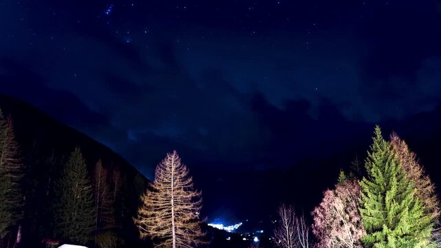 A Timelapse of the nightsky with the small town of Antholz. It has a beautiful mix of clouds and clear sky moving in opposite directions. You can see star constellations like the Orion.