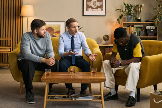Young adult men discussing personal problems during support session, showing male friendship, empathy, counseling. Useful for mental health, peer support, therapy marketing