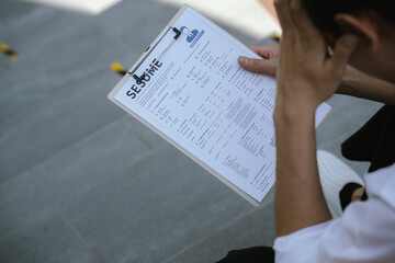 Naklejka premium Job applicant reviewing a resume document before an interview, reflecting career planning, employment opportunities, job search preparation, and professional development.