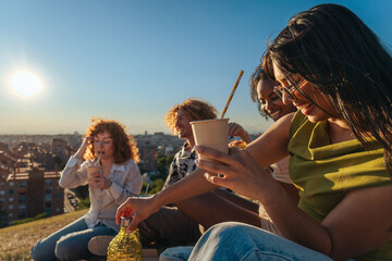 Naklejka premium Diverse friends enjoying picnic outdoors watching city sunset