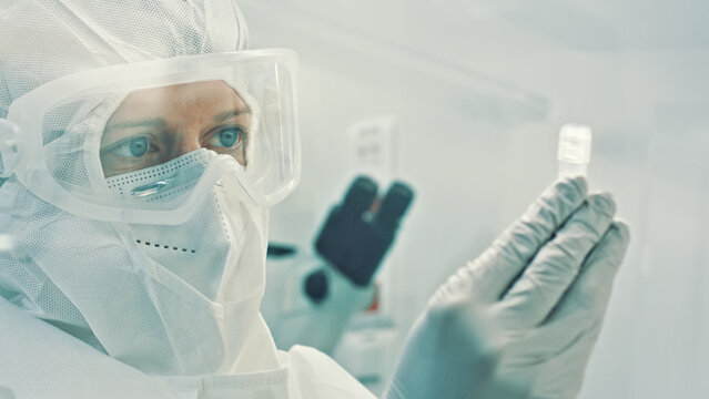 A scientist in a clean suit examines a sample, surrounded by sterile laboratory equipment, highlighting the precision needed in biotechnology and microbiology research.