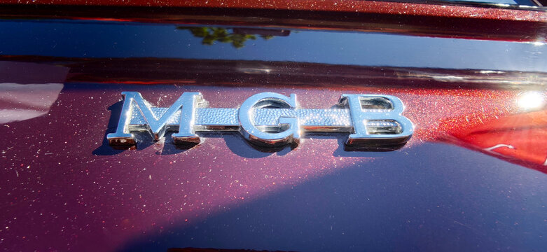 Saint Petersburg, Russia - May 23, 2026: MGB car badge emblem displayed on a classic automobile with shiny red paint reflecting sunlight in a clear outdoor setting