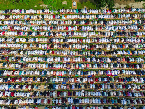 Joypurhat, Bangladesh - 28 May 2026: Aerial view of a large crowd of Muslim men praying in neat rows on colorful prayer mats during a religious gathering outdoors.