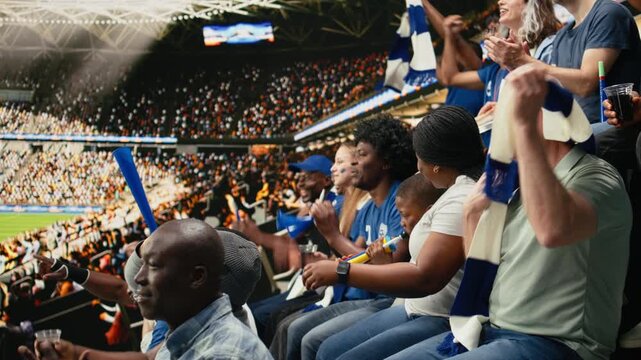 Young soccer fan cheering with blue supporters during live football match in packed stadium filled with cheering supporters, family outing captures fatherhood and role model during soccer experience.