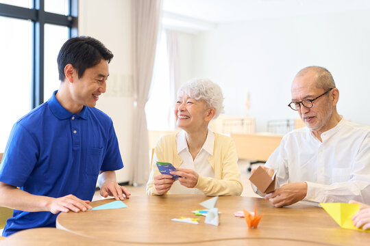 介護施設で折り紙を折るシニアと介護士