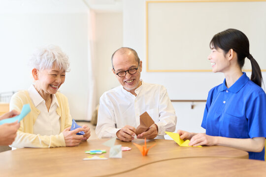 介護施設で折り紙を折るシニアと介護士