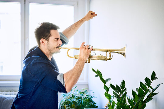 Man at home playing trumpet