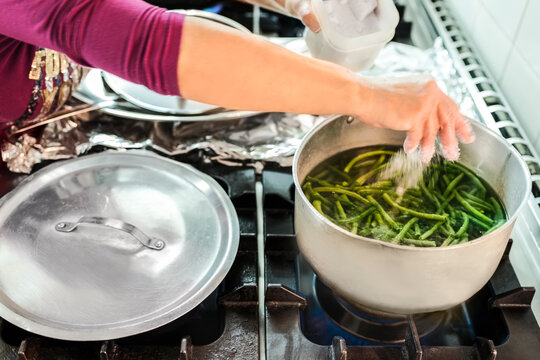 Woman boiling green beans in canteen kitchen