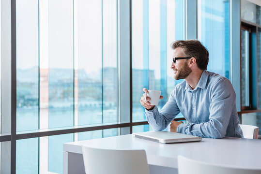 Man with laptop and coffee cup sitting in modern office building