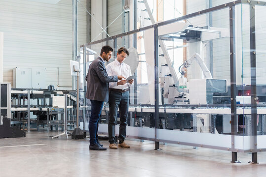 Two businessmen with tablet talking in modern factory
