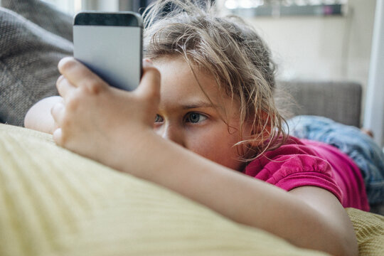 Girl lying on couch using smartphone