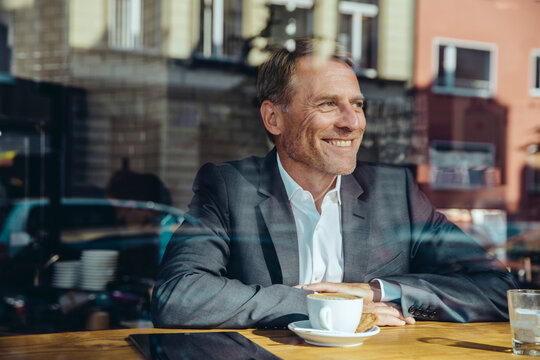 Smiling businessman in cafe looking out of window