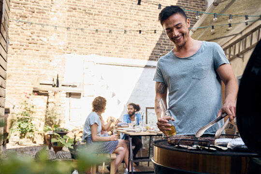 Young man preparing a meat for his friends a ta barbecue party