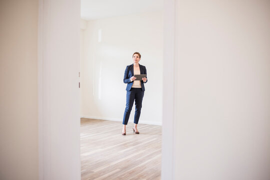 Woman in empty apartment with tablet