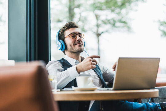 Young man in a cafe with laptop and headphones relaxing