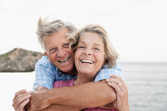 Spain, Senior couple embracing at harbour, smiling