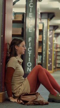 Library, tired woman and sad student with stress, exam fail or education pressure in college. Burnout, university or person with depression on floor for bad grades, assignment deadline or overwhelmed