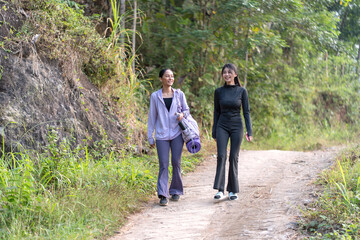 Obraz premium Asian female friends hiking in tropical forest road