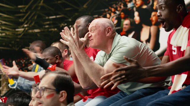 Frustrated football supporters gesturing with open hands in stadium stands, reacting to tense live soccer match moment and close call, anxious crowd shows suspense, last minute pressure.