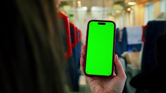 A train passenger holds a phone with a green screen, a person spends time on social networks and whiles away time on trips. High quality 4k footage