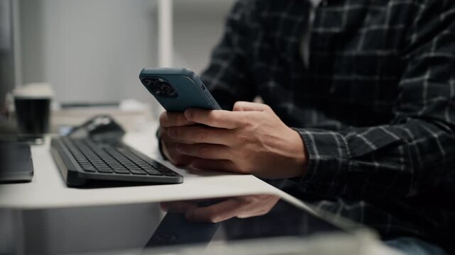Close-up of a man software developer holding smartphone device, working on network server security and cyber privacy system at the office desk.
