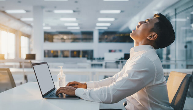Man Sneezing While Typing on Laptop in Modern Office Space