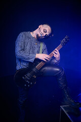 Fototapeta premium Young man with skeletal face paint playing electric guitar in dark moody setting